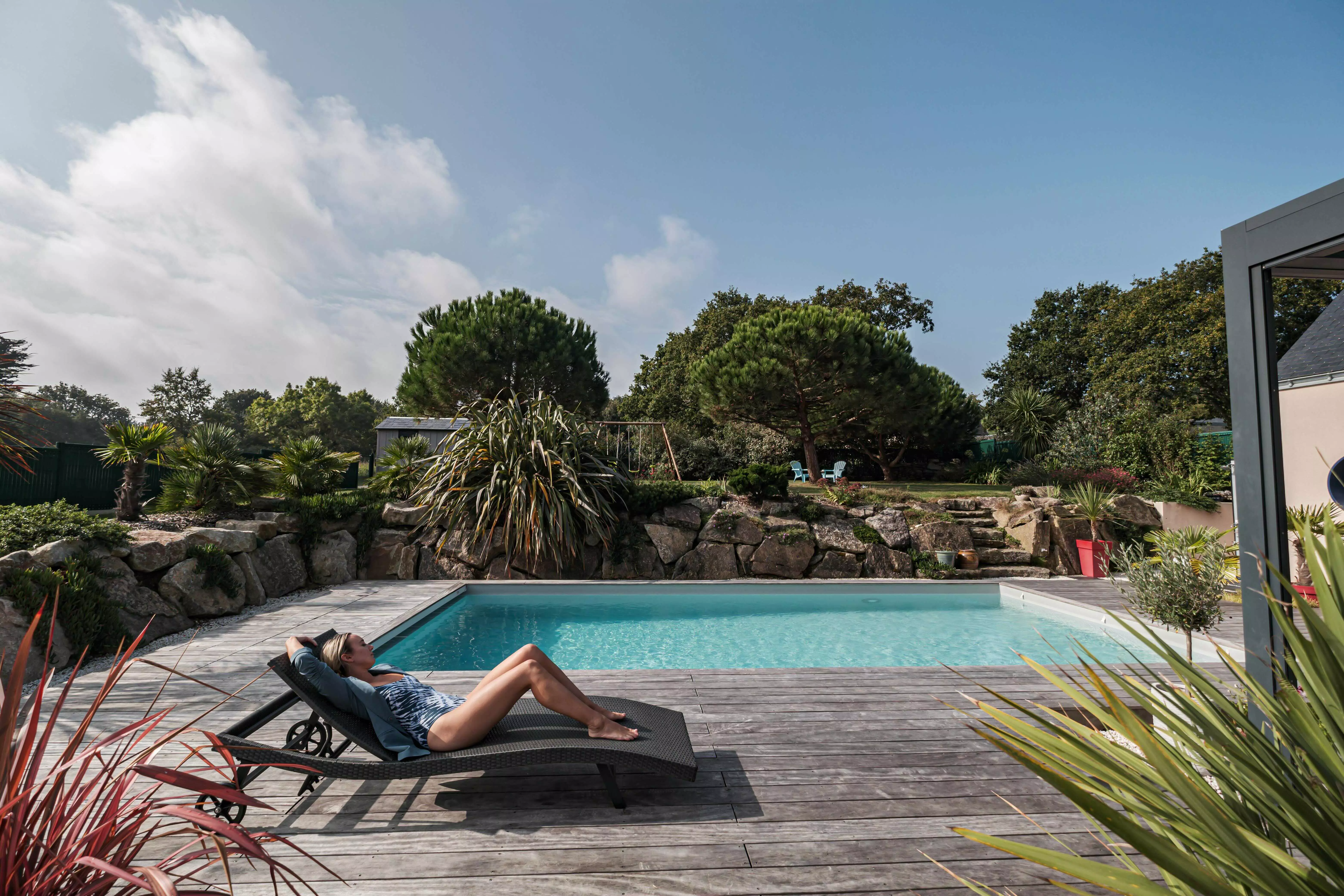 piscine, terrasse bois, avec une femme qui bronze sur un transat