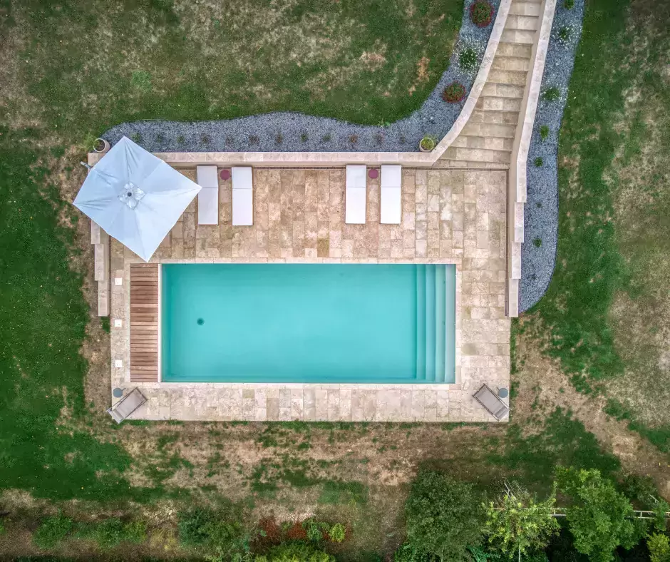 Une piscine avec une palette de couleurs d'olive et une terrasse en travertin.