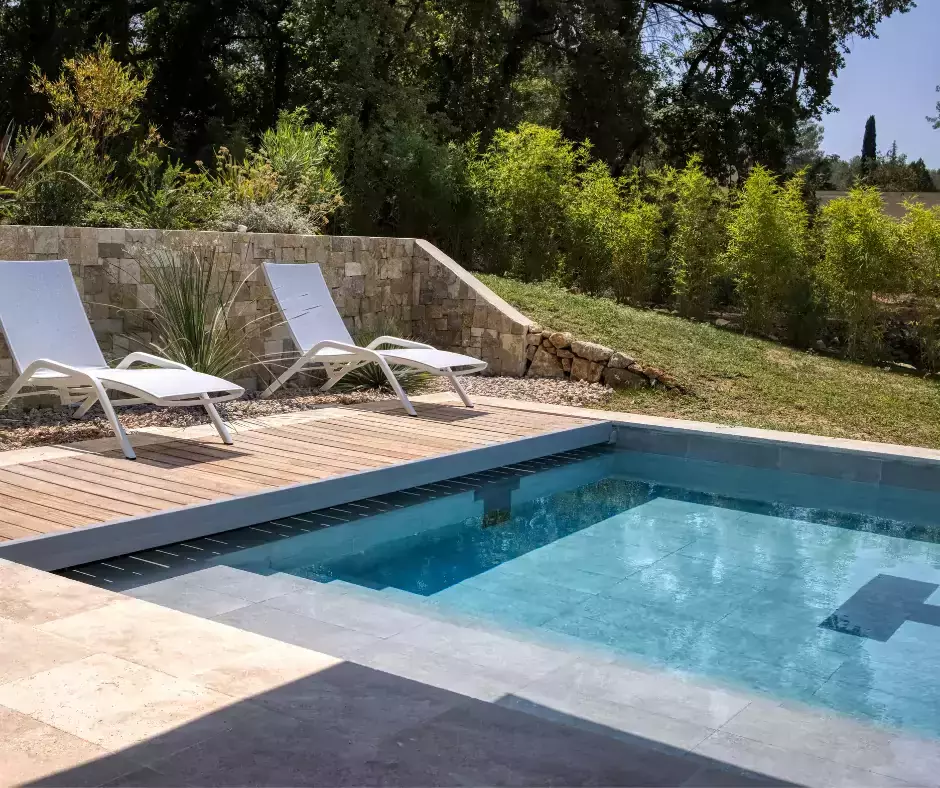 une piscine avec couloir de nage, terrasse en trois zones, et végétation choisie pour rappeler le bord de mer.