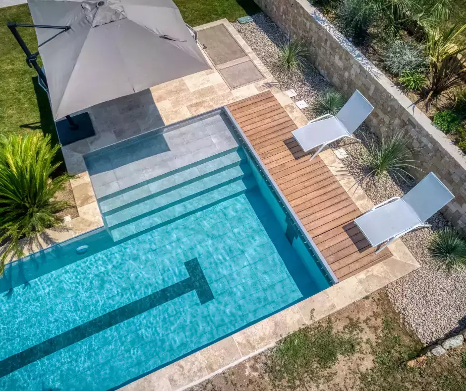 une piscine avec couloir de nage, terrasse modulée en trois espaces, et végétation côtière.