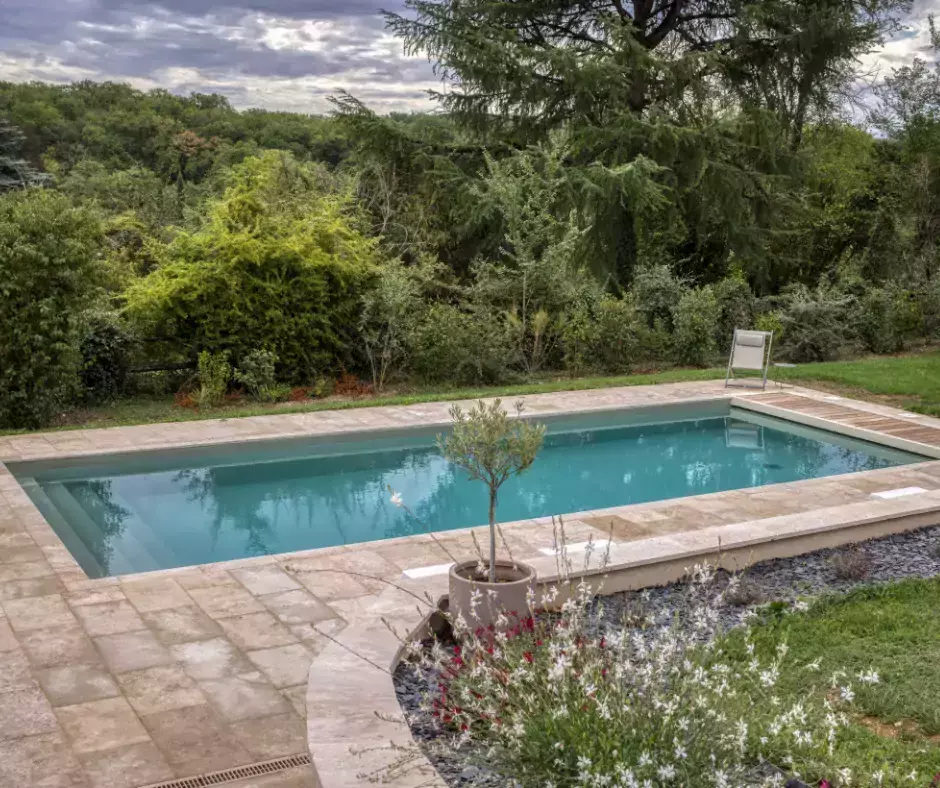 Une piscine aux reflets d'olive, accompagnée d'une terrasse en travertin.