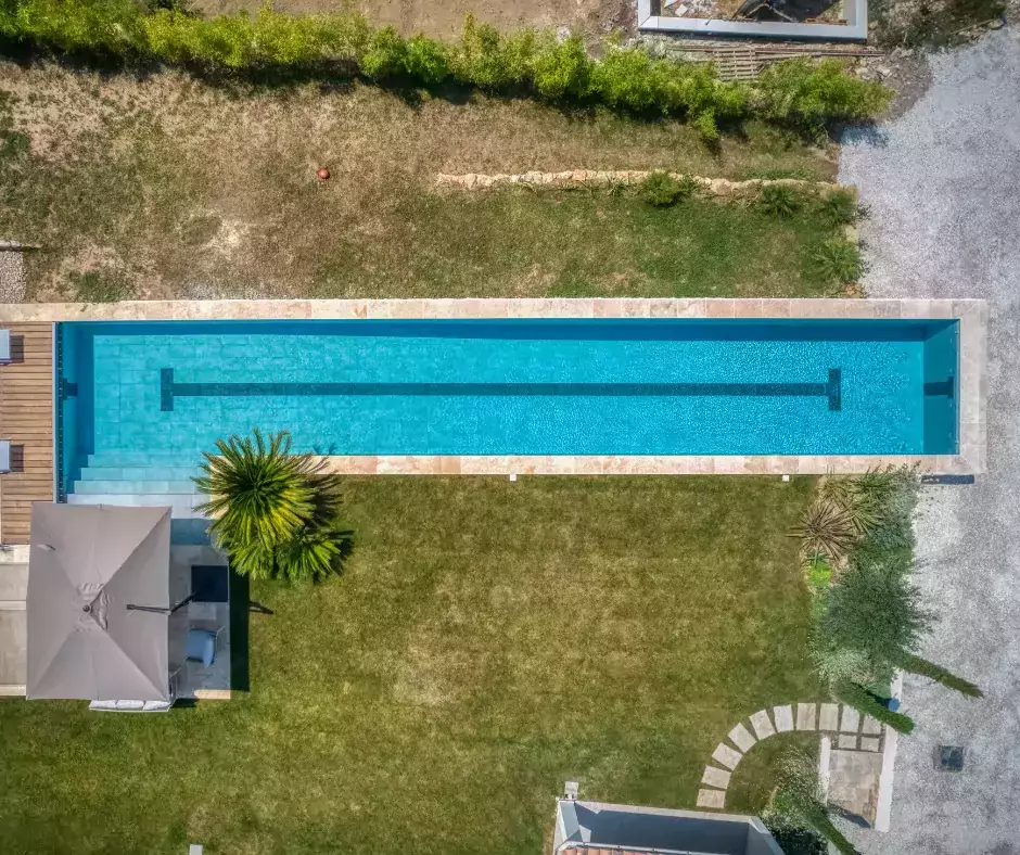 une piscine rectangulaire avec couloir de nage, terrasse aménagée, et végétation maritime pour une ambiance côtière.