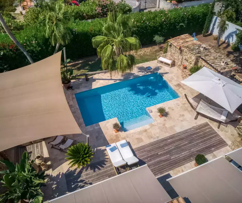 Modernisation d'une piscine coque en piscine en béton, rehaussée par un palmier imposant, un rideau d'eau et une terrasse chic en travertin.