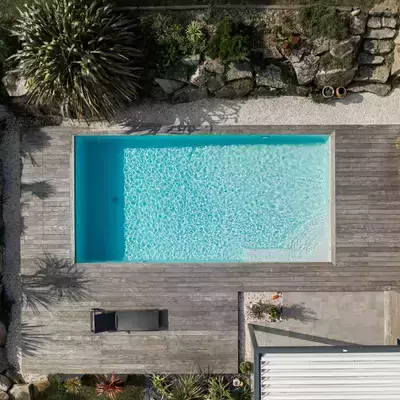 Une construction contemporaine où la piscine est l'élément central, entourée d'une terrasse qui mène à un paysage rocheux parsemé de plantes exotiques.
